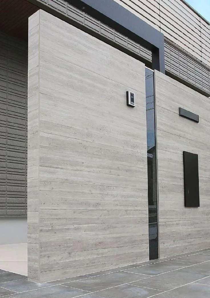 Détail d'une façade en pierre claire avec menuiseries et boîte aux lettres sombres